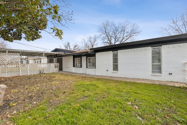 back of property featuring brick siding and a lawn