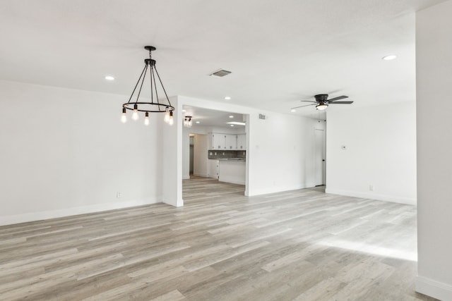 unfurnished living room featuring recessed lighting, visible vents, light wood-style flooring, and ceiling fan with notable chandelier