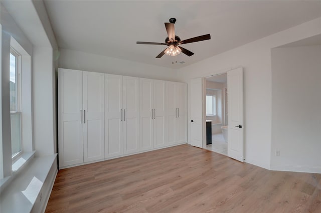 unfurnished bedroom with light wood-style floors, ceiling fan, and baseboards