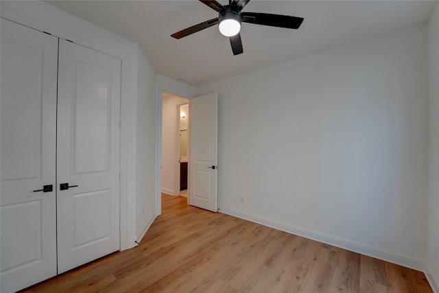 unfurnished bedroom featuring light wood-style floors, a closet, ceiling fan, and baseboards