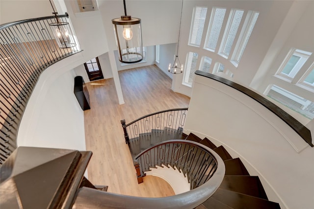 staircase featuring a towering ceiling, a chandelier, and wood finished floors