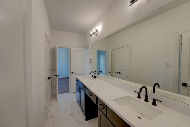 bathroom featuring marble finish floor, double vanity, and a sink