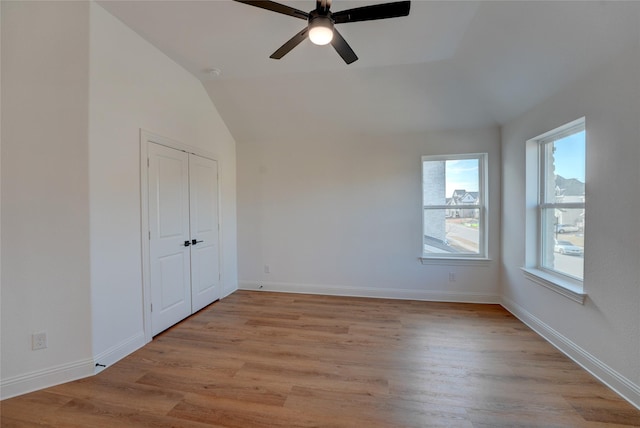 unfurnished bedroom with lofted ceiling, light wood finished floors, ceiling fan, and baseboards