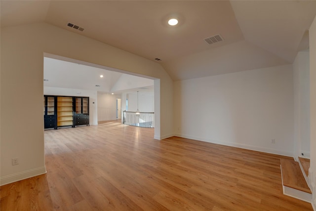 unfurnished living room with lofted ceiling, light wood-style flooring, visible vents, and baseboards