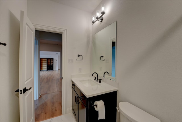 half bath with wood finished floors, vanity, and toilet