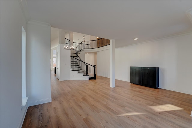 unfurnished living room with baseboards, ornamental molding, wood finished floors, stairs, and a chandelier