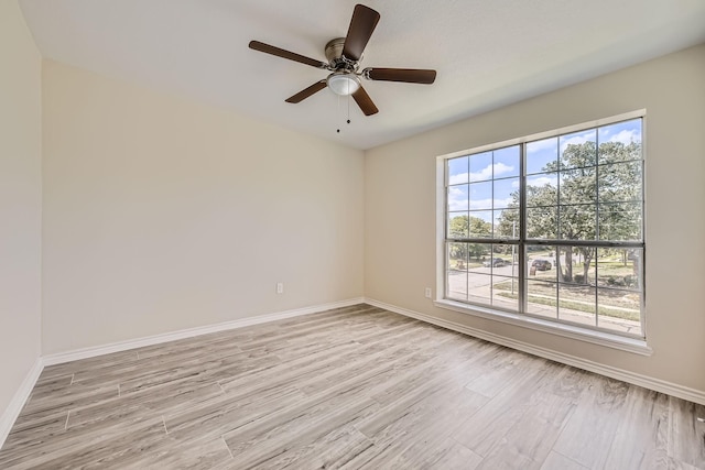 spare room featuring baseboards, ceiling fan, and light wood finished floors