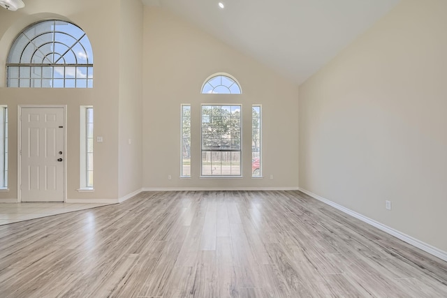 foyer entrance with baseboards, high vaulted ceiling, and light wood-style floors