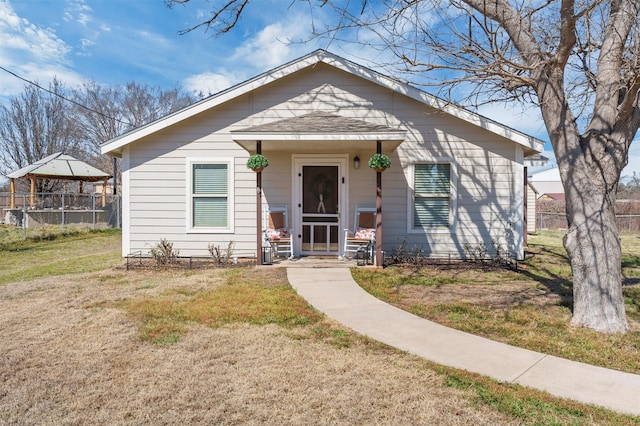 bungalow-style house with fence, a front lawn, and roof with shingles