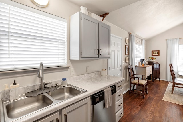 kitchen with dark wood-style floors, light countertops, vaulted ceiling, a sink, and dishwasher