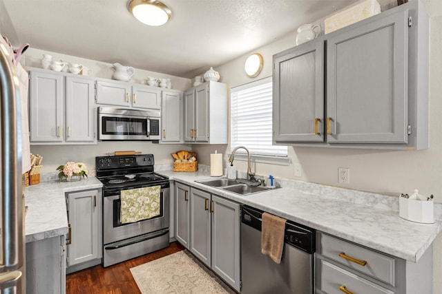 kitchen featuring appliances with stainless steel finishes, dark wood finished floors, a sink, and light countertops