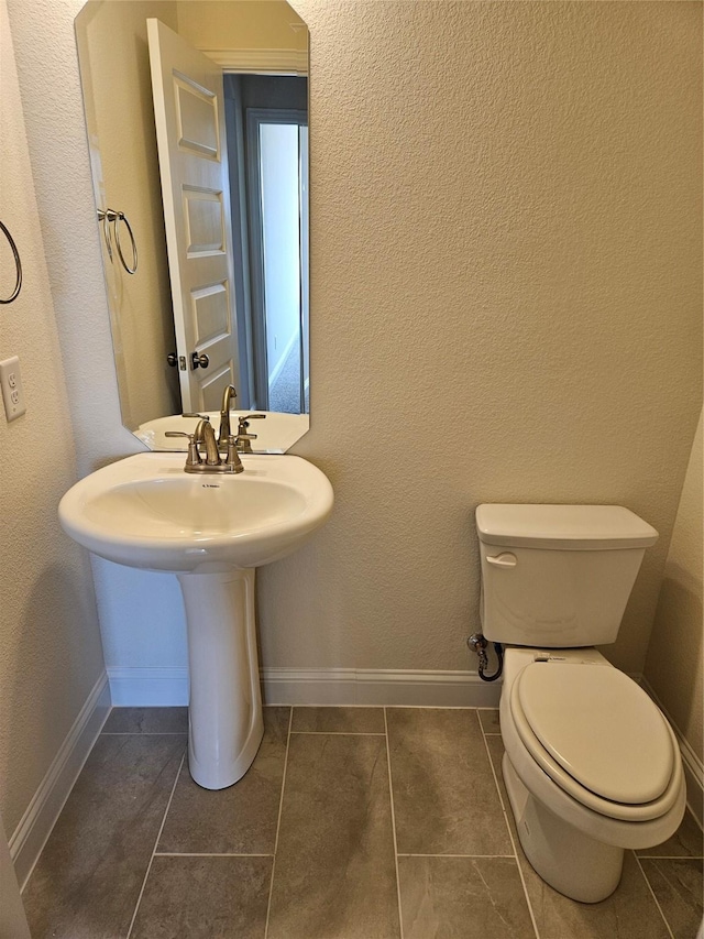 bathroom featuring toilet, baseboards, and tile patterned floors