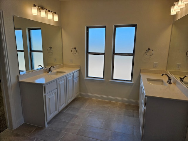 bathroom featuring two vanities, a sink, and baseboards