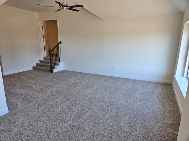 unfurnished room featuring carpet floors, stairs, baseboards, and vaulted ceiling