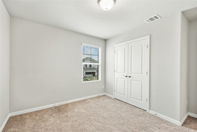 unfurnished bedroom with baseboards, carpet, visible vents, and a closet