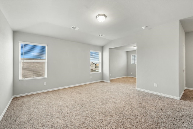 unfurnished room with baseboards, visible vents, and light colored carpet