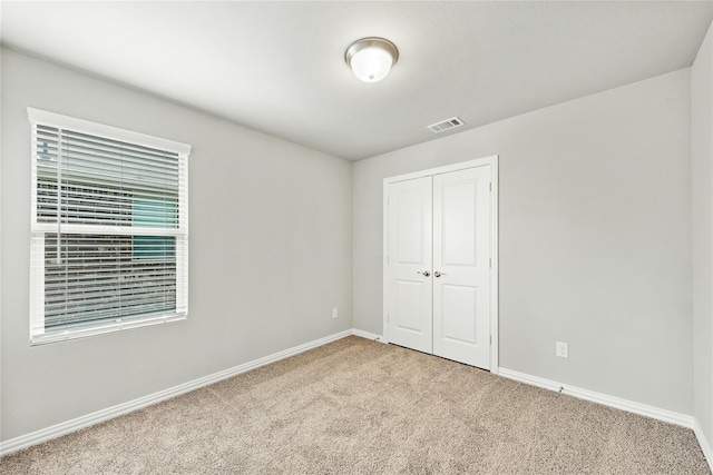 unfurnished bedroom with baseboards, carpet, visible vents, and a closet