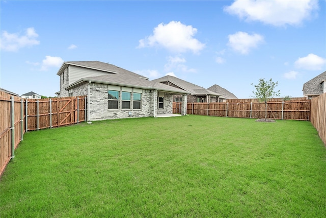 back of house featuring a fenced backyard, a lawn, and brick siding