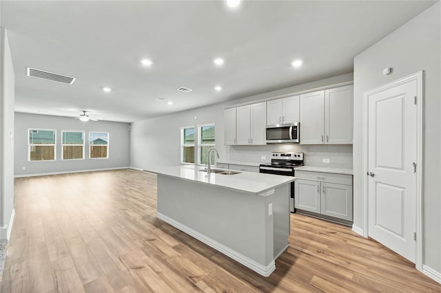 kitchen with a sink, visible vents, light wood-style floors, light countertops, and appliances with stainless steel finishes