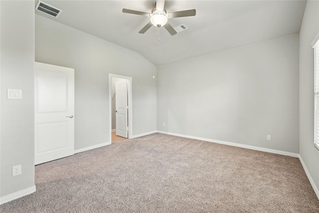 carpeted empty room with lofted ceiling, baseboards, visible vents, and a ceiling fan