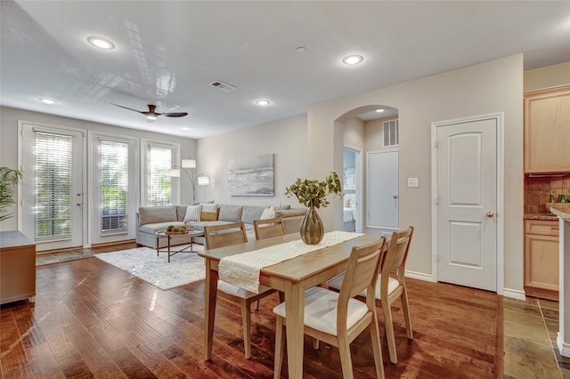 dining space featuring arched walkways, wood finished floors, visible vents, and recessed lighting