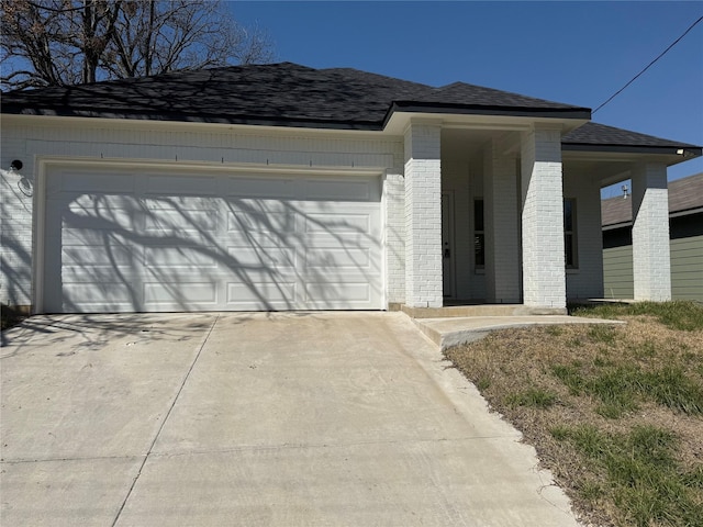 view of front of property with driveway, a shingled roof, a garage, and brick siding