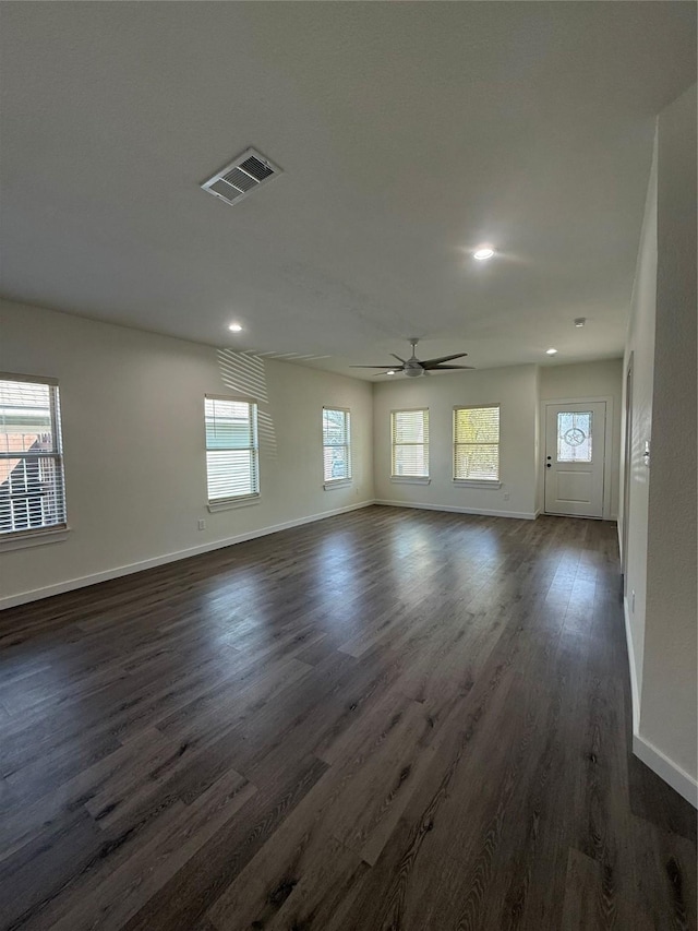 empty room featuring dark wood-style floors, visible vents, and baseboards