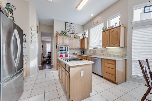 kitchen with light tile patterned flooring, stainless steel appliances, a kitchen island, a sink, and tasteful backsplash