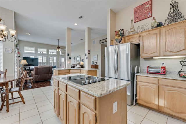 kitchen with light tile patterned floors, black electric cooktop, a kitchen island, freestanding refrigerator, and light brown cabinetry