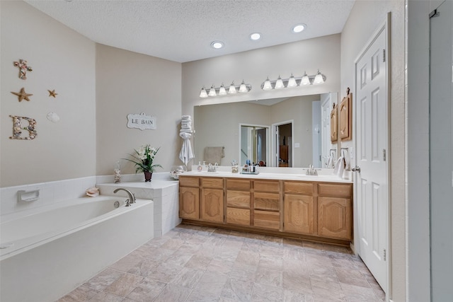 bathroom featuring a garden tub, a sink, a textured ceiling, and double vanity