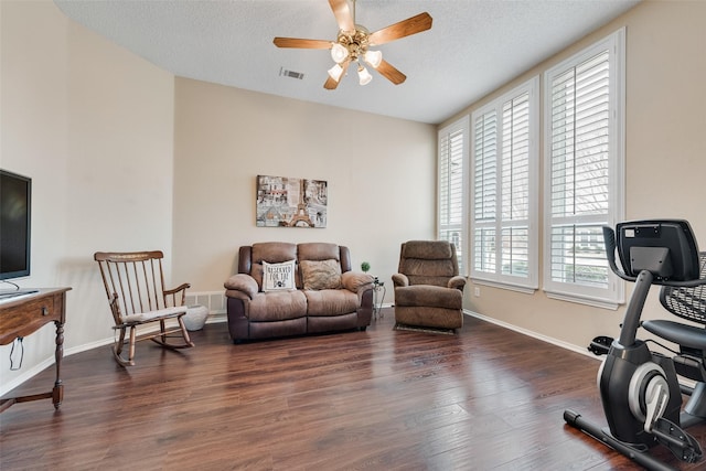 living room with baseboards, visible vents, a ceiling fan, wood finished floors, and a textured ceiling