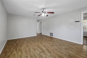 spare room featuring visible vents, baseboards, ceiling fan, and wood finished floors