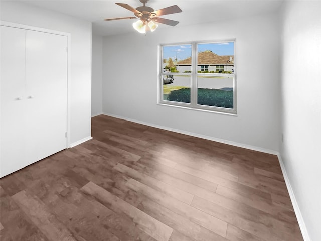 unfurnished bedroom with ceiling fan, a closet, wood finished floors, and baseboards