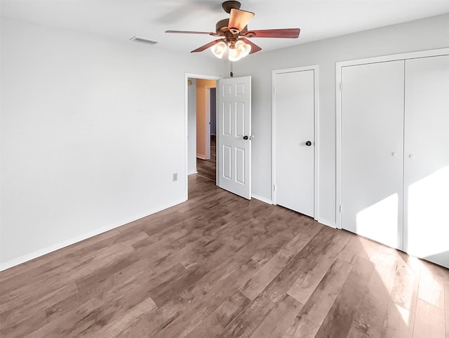 unfurnished bedroom with ceiling fan, wood finished floors, visible vents, and baseboards