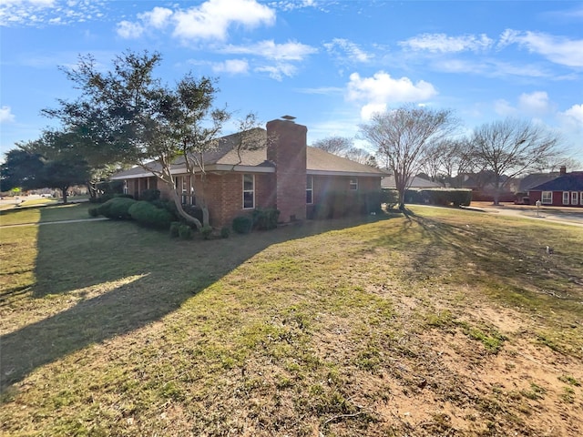 view of property exterior with brick siding, a chimney, and a yard