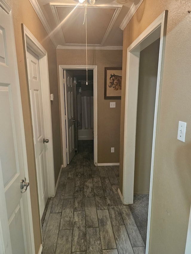 corridor with attic access, wood tiled floor, baseboards, and crown molding