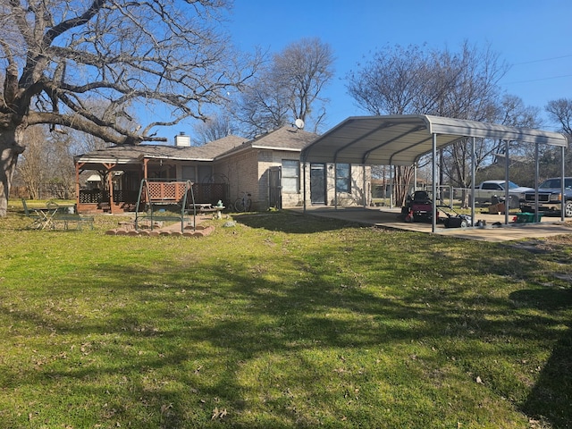 rear view of property featuring brick siding, a detached carport, a chimney, and a yard