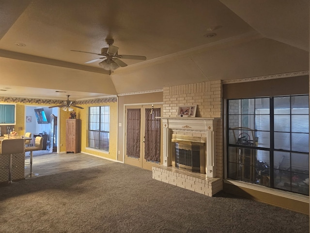 unfurnished living room featuring a raised ceiling, lofted ceiling, ceiling fan, carpet, and a brick fireplace