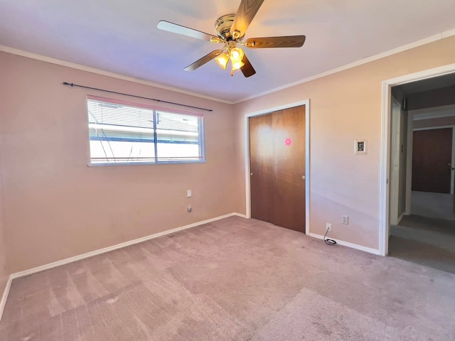 unfurnished bedroom featuring carpet, a closet, crown molding, and baseboards