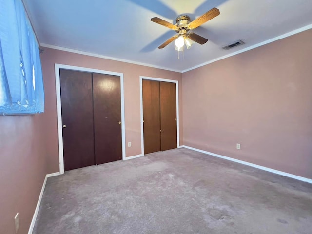 unfurnished bedroom featuring ceiling fan, visible vents, baseboards, ornamental molding, and two closets