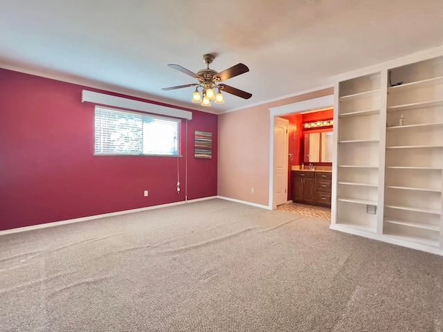 unfurnished bedroom with ceiling fan, connected bathroom, light colored carpet, baseboards, and crown molding