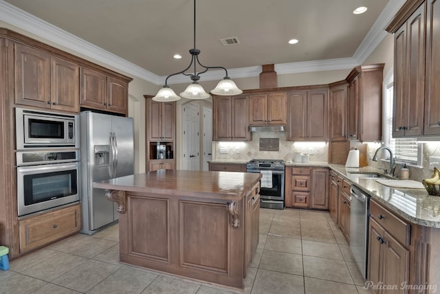 kitchen featuring under cabinet range hood, stainless steel appliances, a sink, visible vents, and a center island