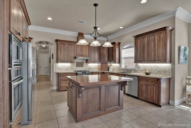 kitchen with arched walkways, visible vents, appliances with stainless steel finishes, a sink, and butcher block countertops