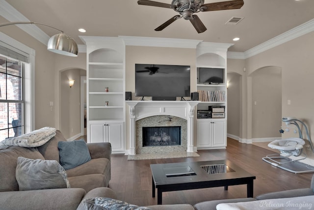 living area featuring arched walkways, visible vents, a premium fireplace, ornamental molding, and wood finished floors