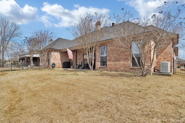 back of property with a chimney, fence, central AC unit, and brick siding