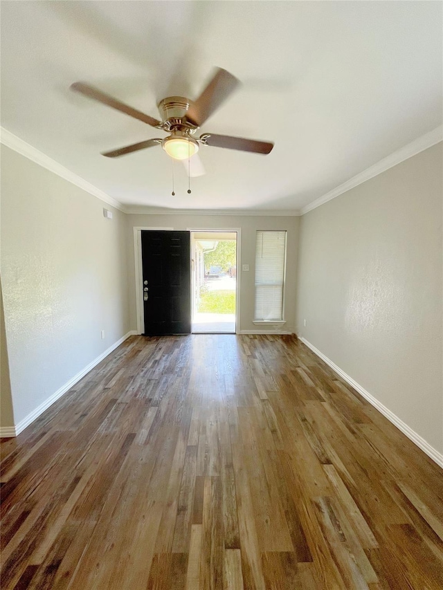 interior space featuring a ceiling fan, baseboards, ornamental molding, and wood finished floors