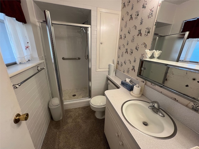 full bathroom with tile walls, toilet, vanity, a shower stall, and wallpapered walls