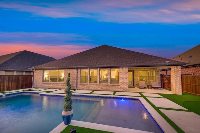 pool at dusk featuring a fenced in pool, a patio area, and a fenced backyard