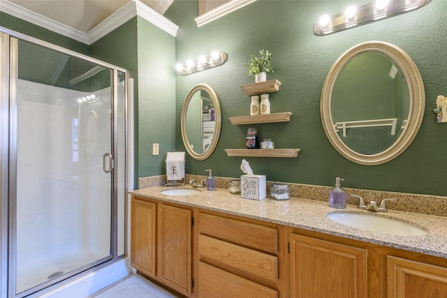 full bath featuring double vanity, a stall shower, a sink, and crown molding