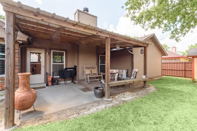 back of house with a patio area, a chimney, fence, and a lawn